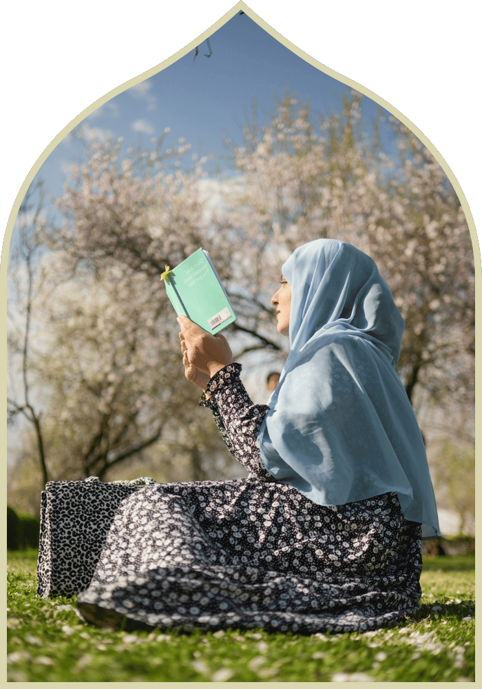 muslim woman in nature sitting reading a book